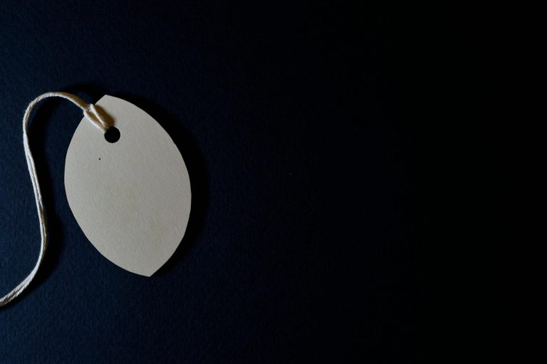 Close-up of a blank paper tag with string on a dark background, perfect for customizable designs.