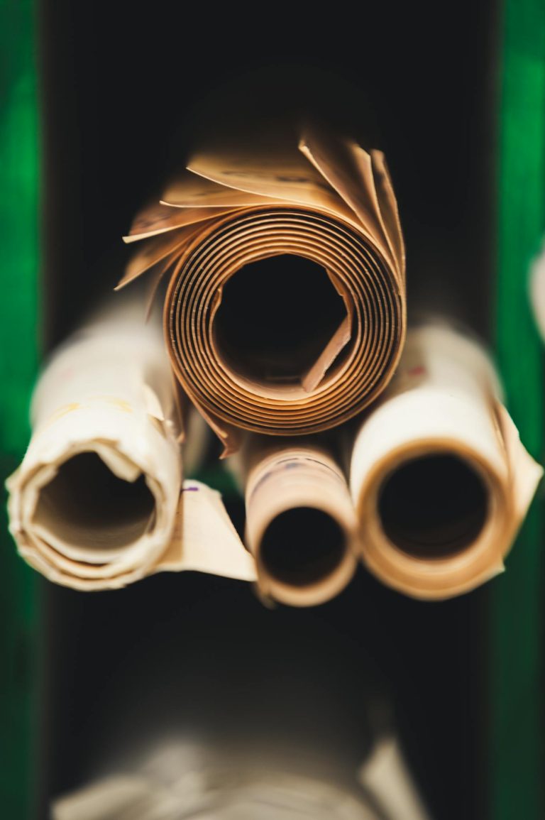 Rolled paper sheets stacked in a workshop setting, showcasing craftsmanship and industry.